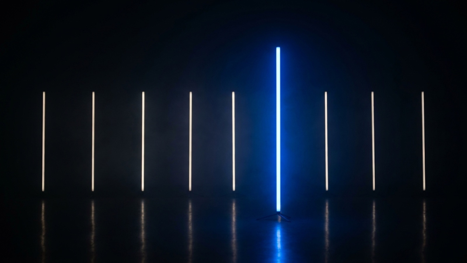 Fila de barras de luz blanca tenue en la oscuridad con una barra azul brillante que sobresale
