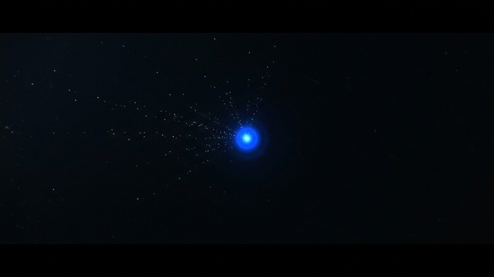 Puntos de luz tenue en la oscuridad convergiendo en un único nodo azul brillante
